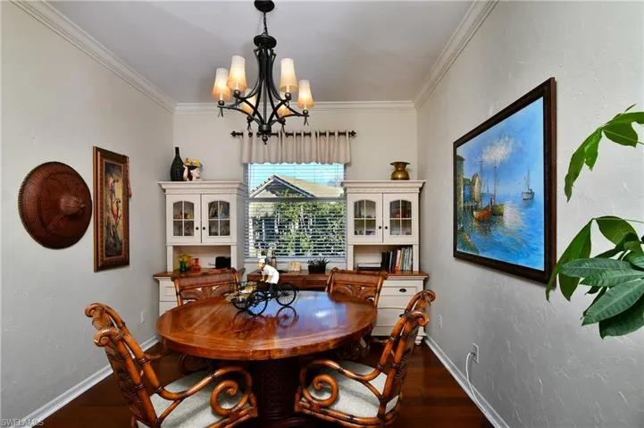 Dining area with dark hardwood / wood-style flooring, a notable chandelier, and crown molding