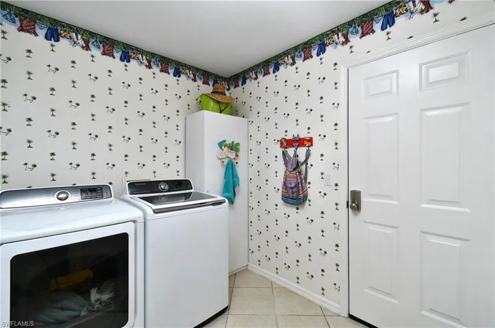 Washroom with washer and clothes dryer and light tile patterned flooring