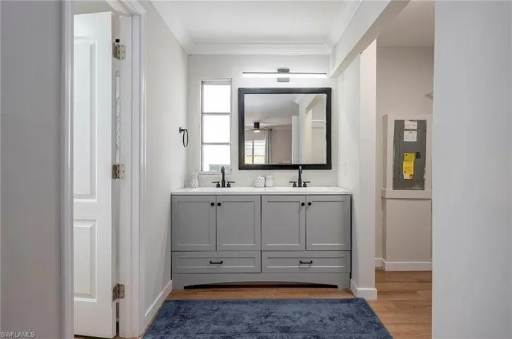 Bathroom with hardwood / wood-style flooring, ornamental molding, oversized vanity, and dual sinks