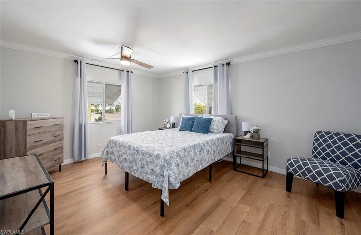 Bedroom with ornamental molding, ceiling fan, light wood-type flooring, and multiple windows