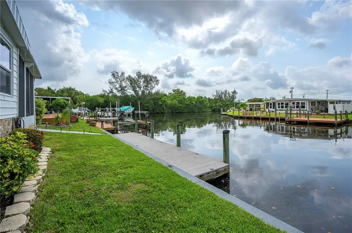 View of dock with a lawn and a water view