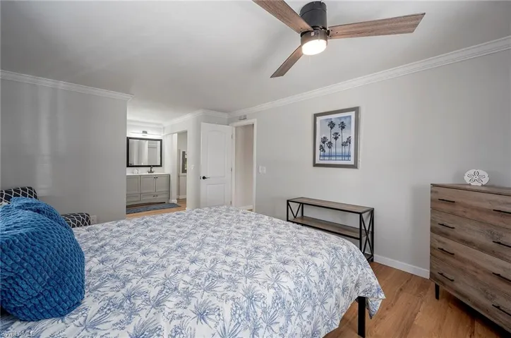 Bedroom with ceiling fan, crown molding, ensuite bathroom, and wood-type flooring
