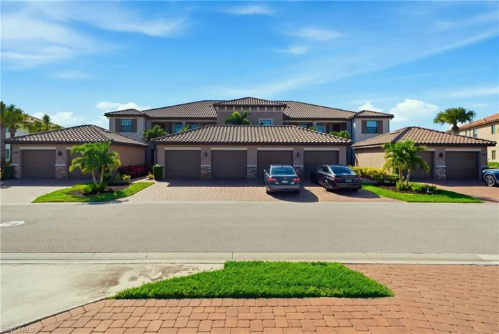 Multi-unit exterior featuring a tile roof, paver driveway, multiple garage bays, and integrated landscaping