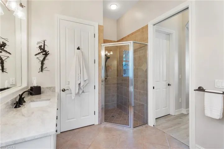 Bathroom featuring walk in shower, vanity, and tile patterned flooring