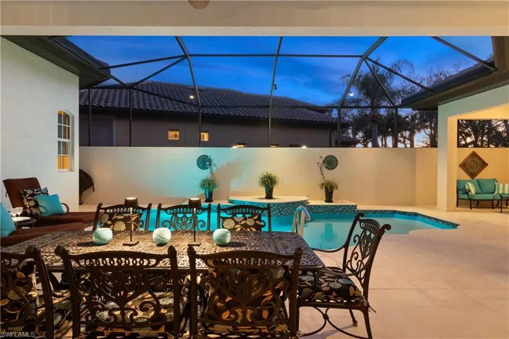 Patio terrace at dusk with a lanai and a fenced in pool