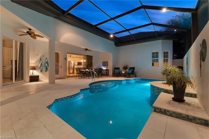 Pool at dusk with ceiling fan, a lanai, and a patio