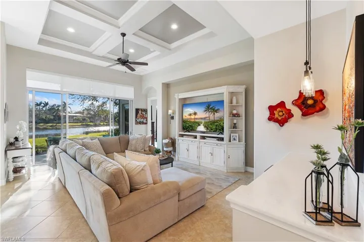 Living room featuring a towering ceiling, coffered ceiling, light tile patterned floors, ceiling fan, and beam ceiling