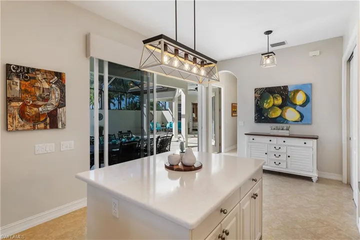 Kitchen featuring a center island, pendant lighting, white cabinets, and light tile patterned floors