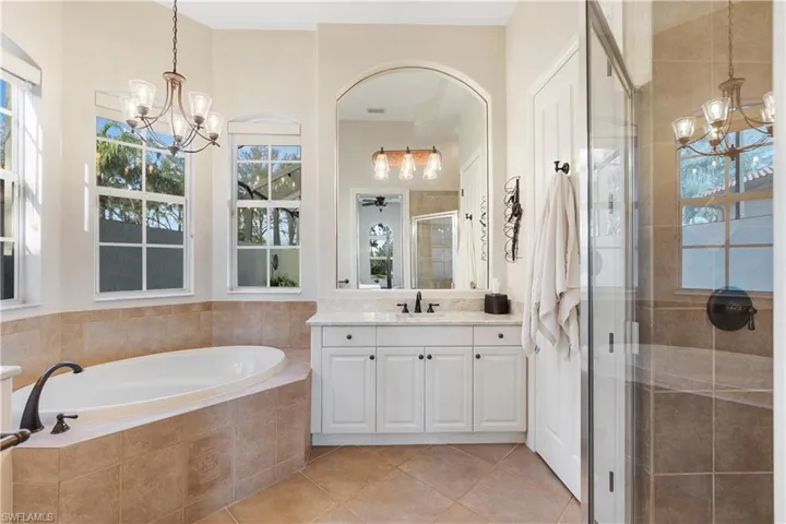 Bathroom featuring tile patterned floors, vanity, independent shower and bath, and a notable chandelier