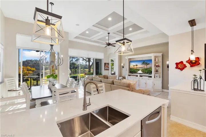 Kitchen featuring sink, hanging light fixtures, plenty of natural light, a high ceiling, and coffered ceiling