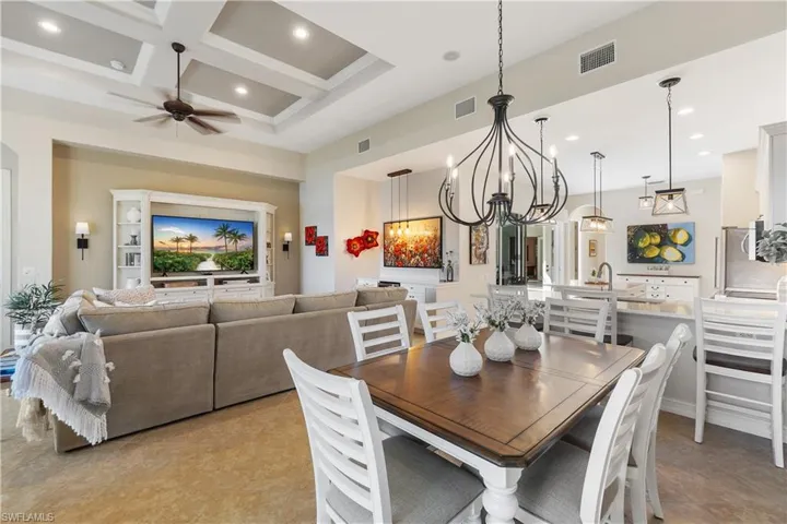 Dining area with coffered ceiling, ceiling fan with notable chandelier, beamed ceiling, and a high ceiling