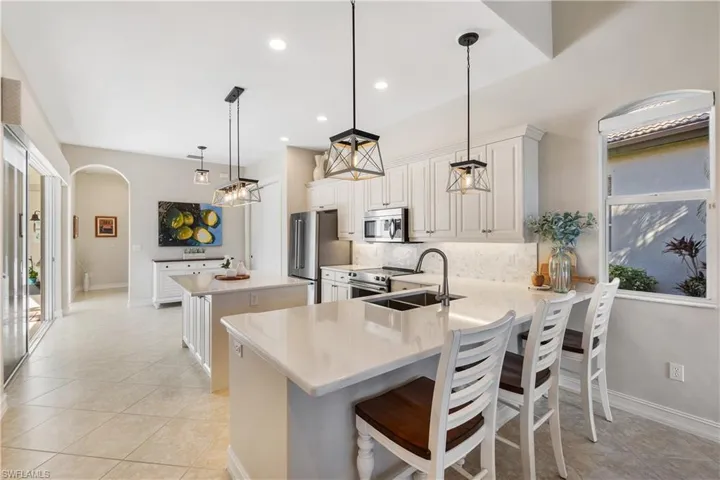 Kitchen featuring tasteful backsplash, a breakfast bar area, hanging light fixtures, kitchen peninsula, and stainless steel appliances