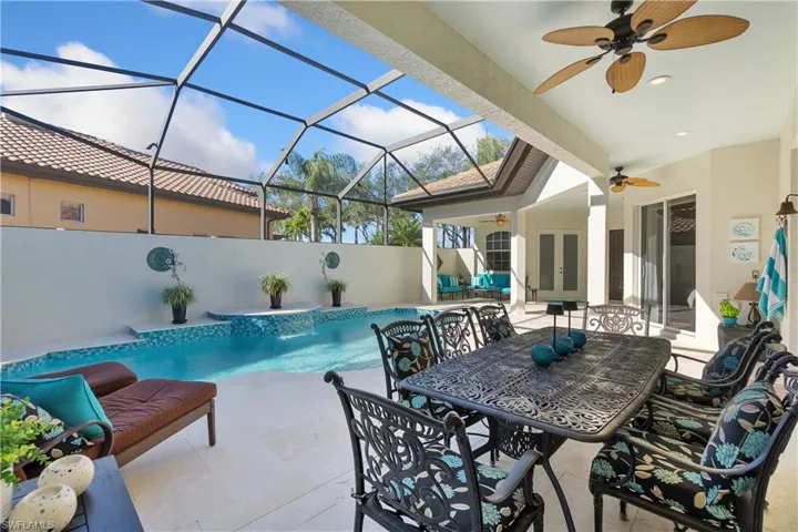 View of pool with a patio area, pool water feature, ceiling fan, and glass enclosure