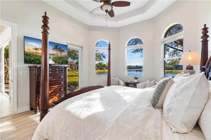 Bedroom featuring access to exterior, a tray ceiling, ceiling fan, and light wood-type flooring