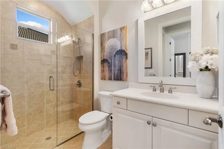 Bathroom featuring an enclosed shower, vanity, and toilet