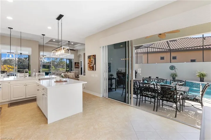 Kitchen with sink, white cabinetry, a center island, hanging light fixtures, and light tile patterned floors