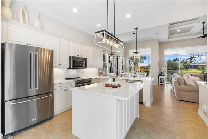 Kitchen featuring white cabinets, hanging light fixtures, a kitchen island, and premium appliances