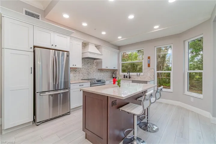 Kitchen featuring white cabinetry, a kitchen island, stainless steel appliances, and custom range hood