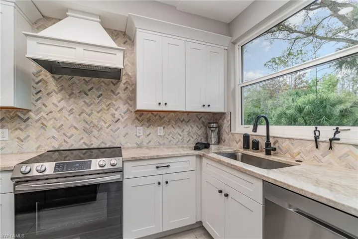Kitchen with white cabinetry, stainless steel appliances, sink, and decorative backsplash