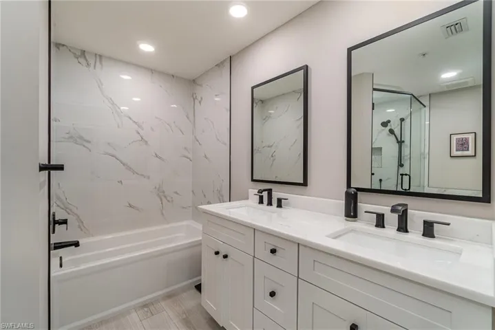 Primary Bathroom with separate walk-in shower and tub, tile flooring, and vanity with dual sinks