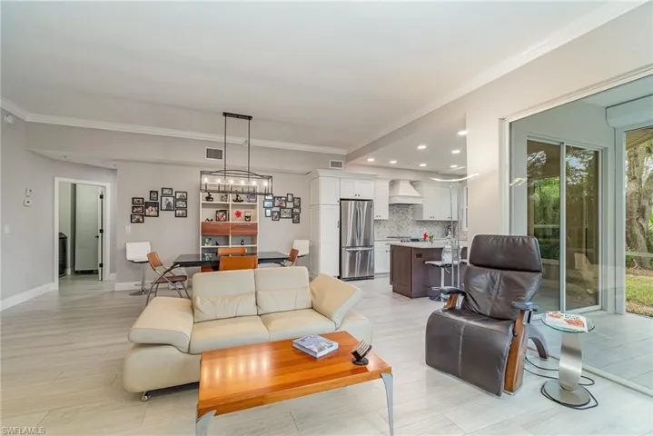 Living room with crown molding, light tile flooring, and plenty of natural light