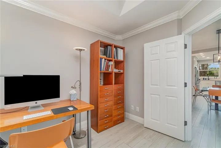 Den featuring crown molding and light tile flooring