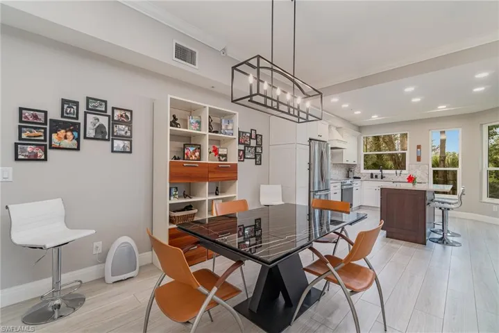 Dining space featuring crown molding, modern light fixture, and light tile floors