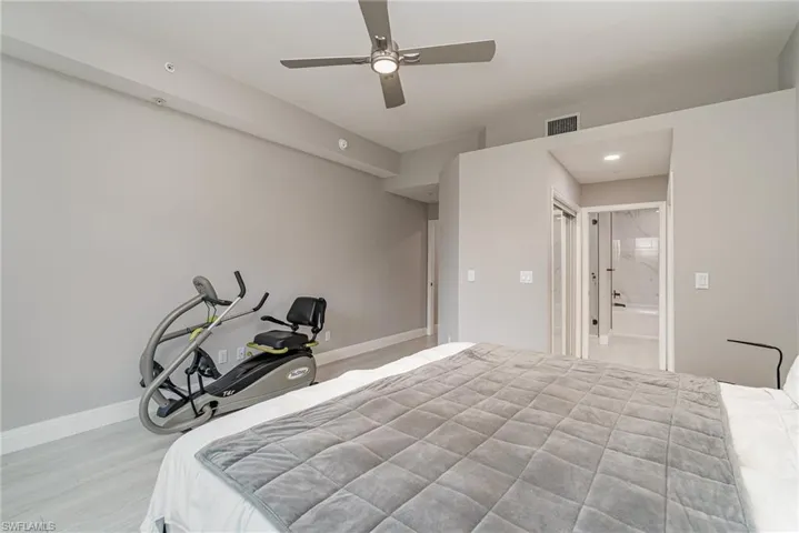 Primary Bedroom featuring light tile flooring, ensuite bath, and ceiling fan