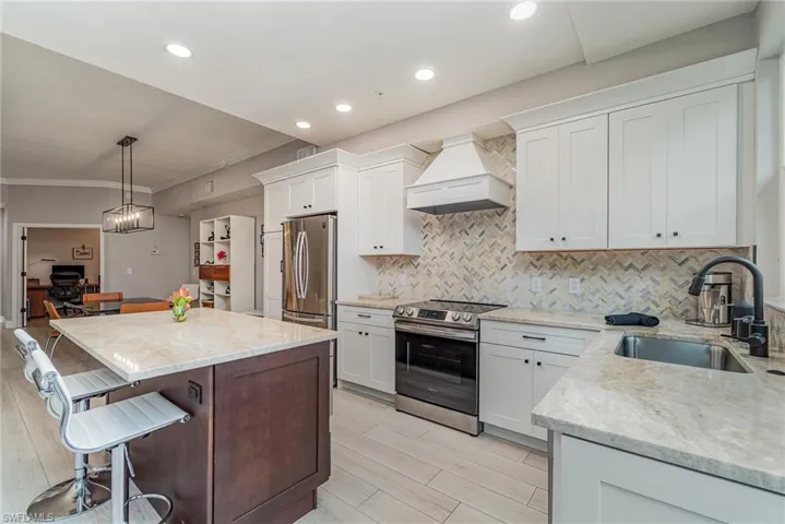 Kitchen featuring custom range hood, appliances with stainless steel finishes, and white cabinetry