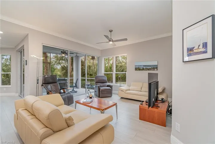 Living room featuring light tile flooring, ceiling fan, and crown molding