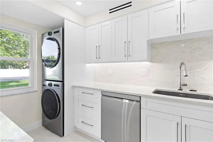Washroom with stacked washer and dryer, sink, and a wealth of natural light