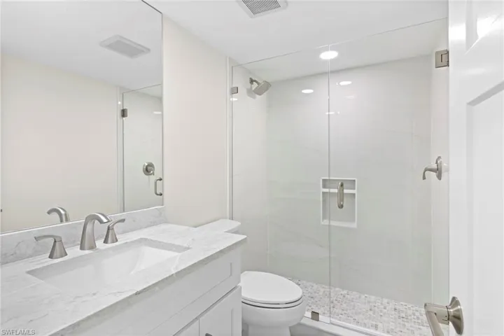 Bathroom featuring toilet, vanity, and an enclosed shower