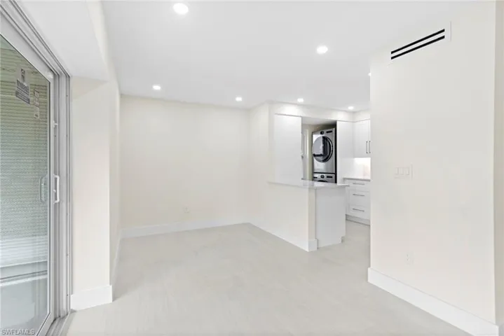 Unfurnished living room with light tile patterned flooring and stacked washer / drying machine