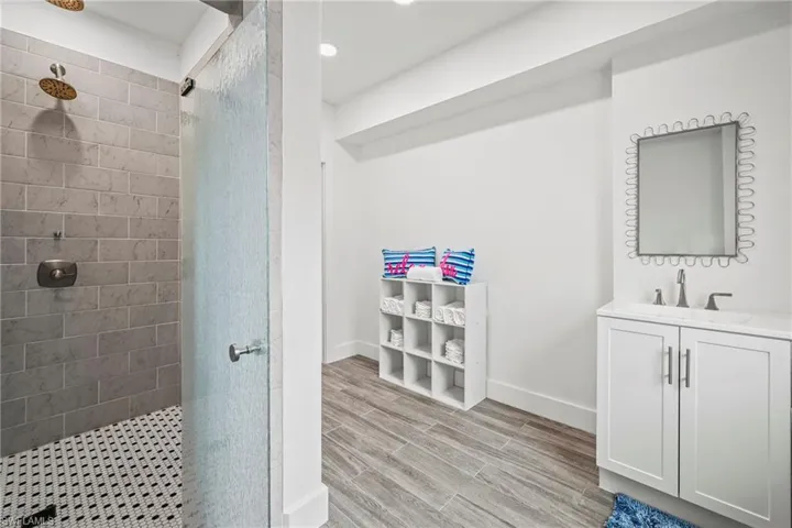 Full bath with a stall shower, vanity, wood finish floors, and recessed lighting