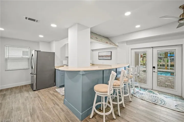 Kitchen with recessed lighting, freestanding refrigerator, a breakfast bar, light wood-style floors, and ceiling fan