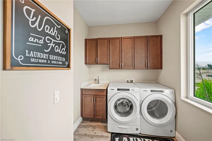 Laundry area featuring healthy amount of natural light, light wood-style floors, washer and dryer, and cabinet space