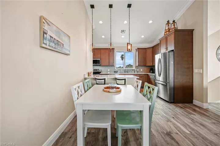 Kitchen with stainless steel appliances, pendant lighting, brown cabinets, light wood finished floors, and decorative backsplash