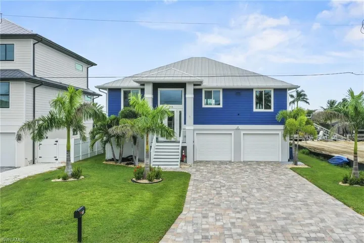Coastal home featuring stairs, a front yard, decorative driveway, and a garage