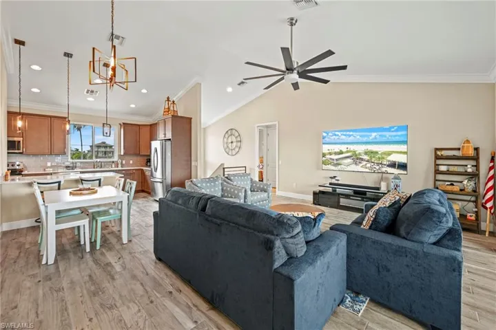 Living area featuring ornamental molding, vaulted ceiling, light wood-style floors, recessed lighting, and ceiling fan