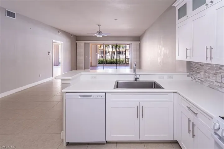 Kitchen featuring a peninsula, white appliances, white cabinetry, light countertops, and light tile patterned flooring