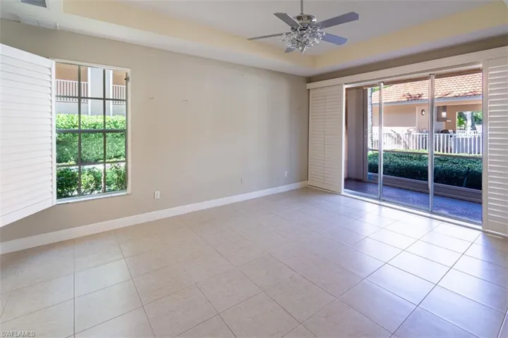 Spare room featuring light tile patterned flooring, ceiling fan, and a raised ceiling