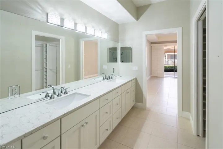 Bathroom featuring a spacious closet, double vanity, and light tile patterned floors