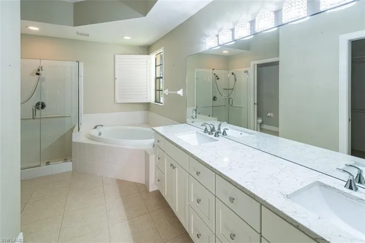Bathroom with a stall shower, double vanity, a garden tub, light tile patterned floors, and recessed lighting