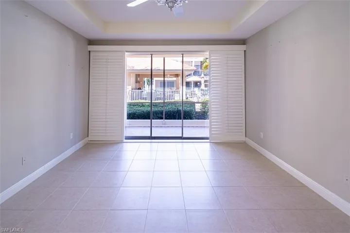 Spare room featuring a raised ceiling, light tile patterned floors, and a ceiling fan