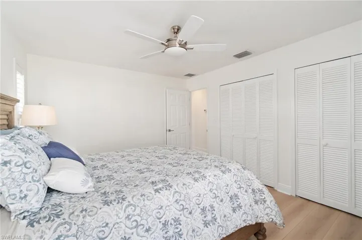 Bedroom featuring two closets, light wood-type flooring, and a ceiling fan