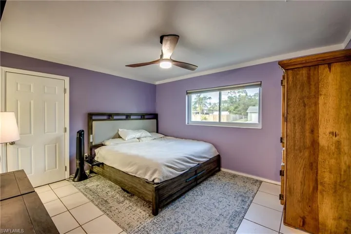 Bedroom with ornamental molding, light tile patterned flooring, and ceiling fan