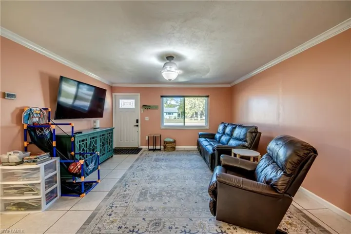 Living room featuring light tile patterned flooring and crown molding