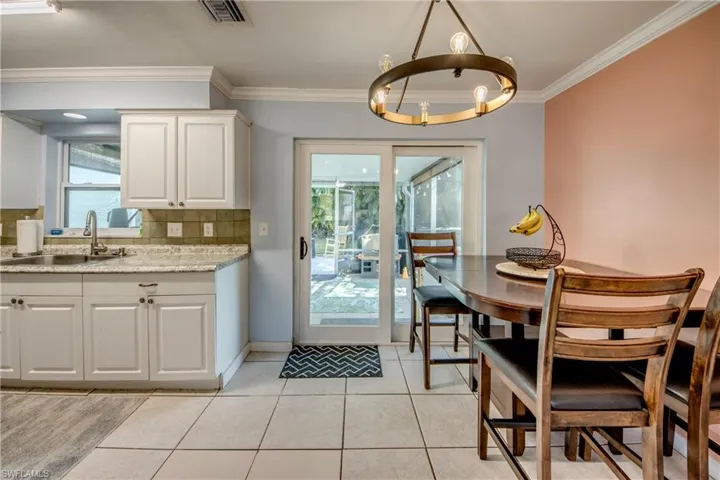 Dining room with light tile patterned flooring, ornamental molding, and a chandelier