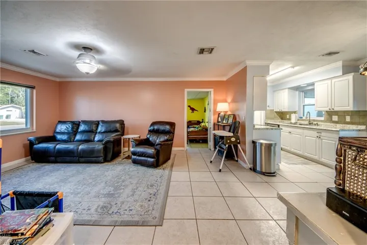 Living room with plenty of natural light, ceiling fan, crown molding, and light tile patterned floors