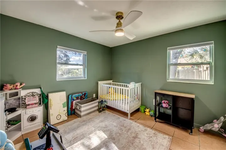 Tiled bedroom with a nursery area, multiple windows, and ceiling fan